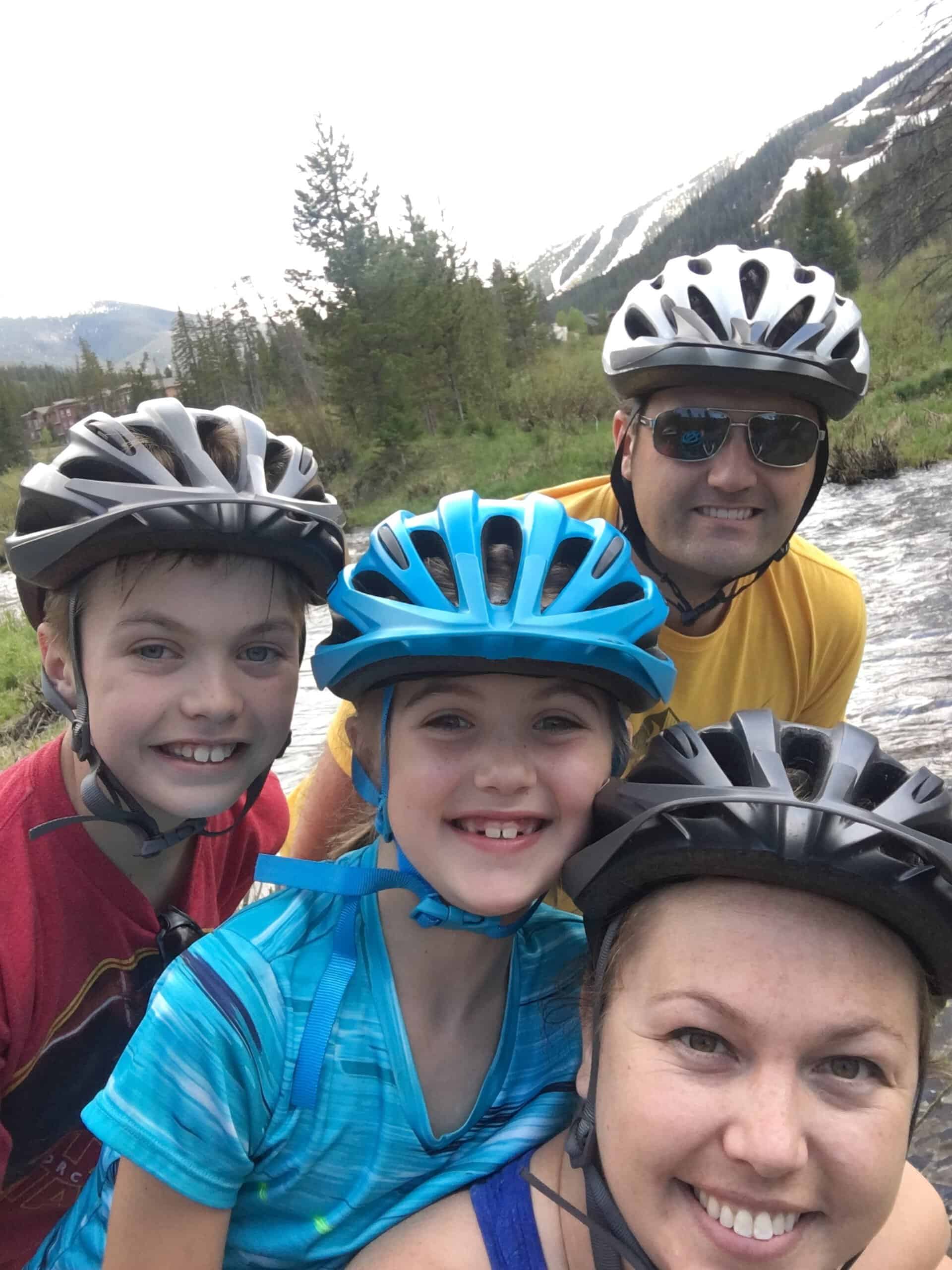 Family of four wearing biking helmets.