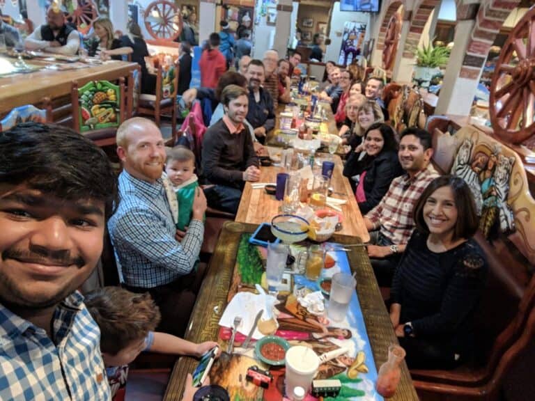 Group of diverse people enjoying a meal together at a restaurant, representing teamwork and community, aligned with Twin State Technical Services' commitment to client collaboration and support.