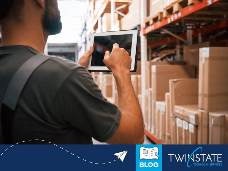 Warehouse worker using a tablet to manage inventory in a multi-site warehouse, highlighting efficient stock control and technology solutions for inventory chaos.